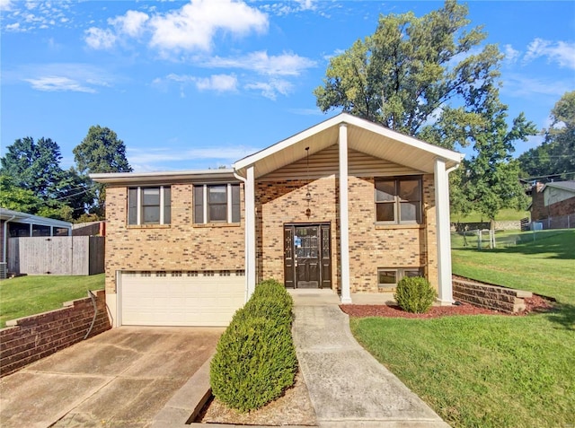 raised ranch featuring a garage, concrete driveway, fence, a front yard, and brick siding