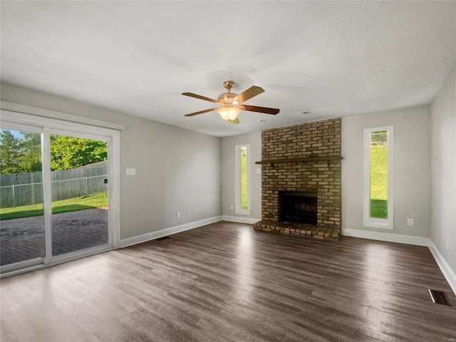 unfurnished living room with a healthy amount of sunlight, dark hardwood / wood-style floors, and a brick fireplace