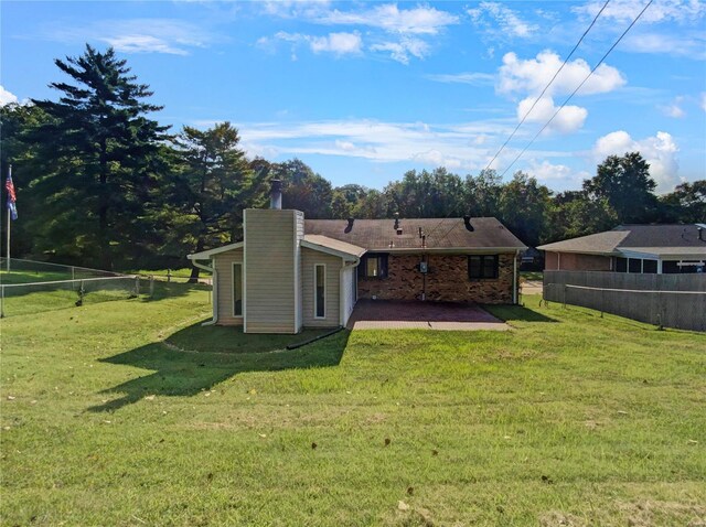 rear view of house featuring a lawn and a patio