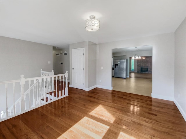 empty room with wood-type flooring and an inviting chandelier