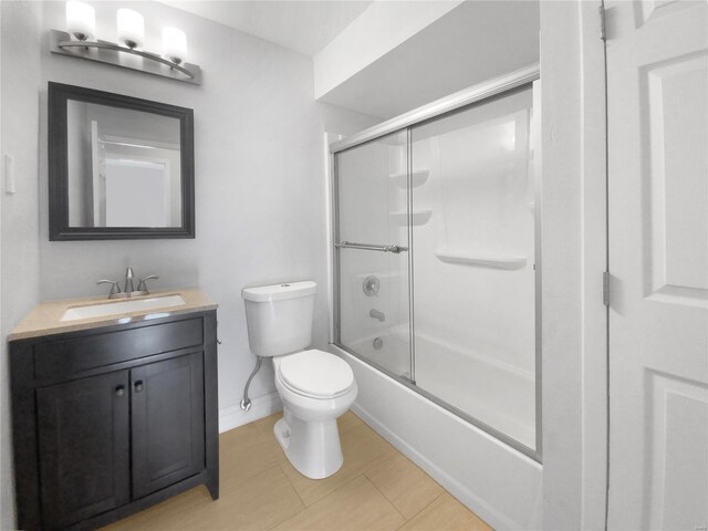 full bathroom with shower / bath combination with glass door, vanity, toilet, and tile patterned flooring