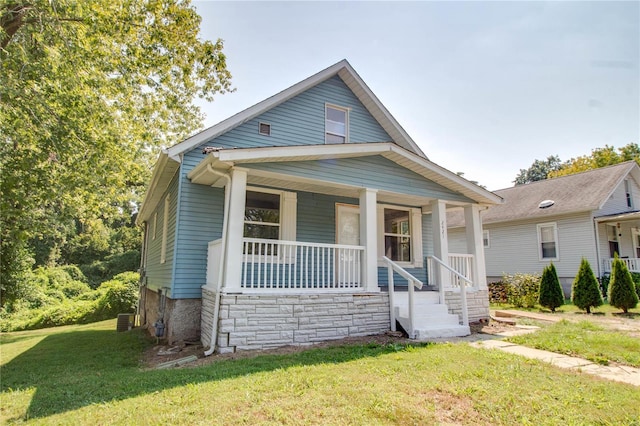 bungalow-style house featuring a porch, a front yard, and central AC