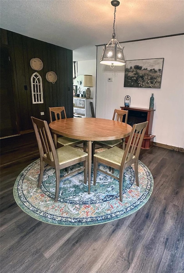 dining room featuring a textured ceiling, dark hardwood / wood-style floors, and wood walls