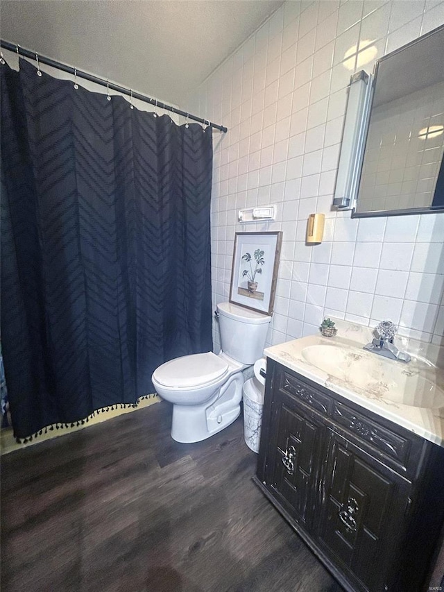 bathroom with vanity, toilet, walk in shower, tile walls, and hardwood / wood-style floors