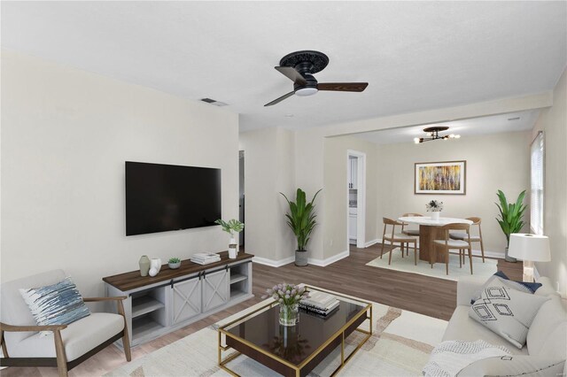 living room with hardwood / wood-style floors and ceiling fan with notable chandelier