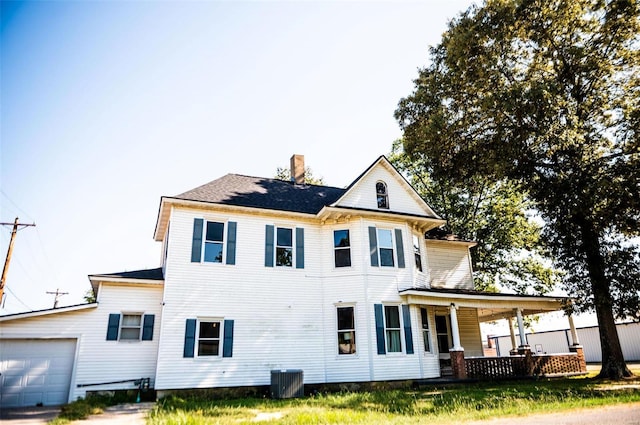 rear view of house with a garage, a porch, and central AC