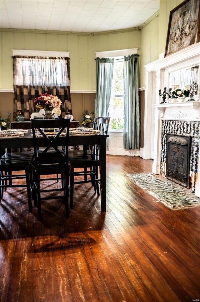 dining room with a tiled fireplace and dark hardwood / wood-style floors