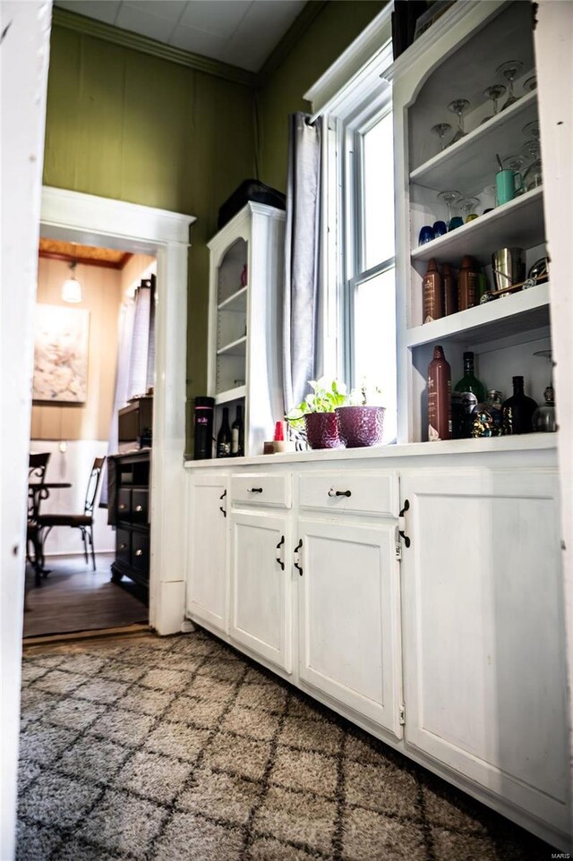 bar with wood-type flooring, white cabinetry, and ornamental molding