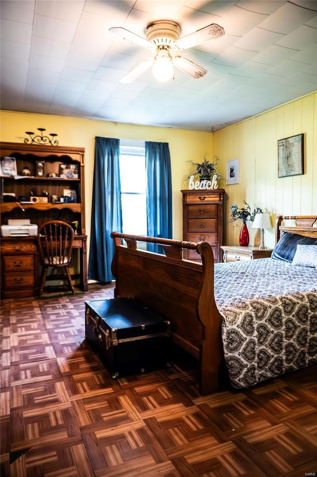 bedroom featuring ceiling fan, wood walls, and dark parquet floors