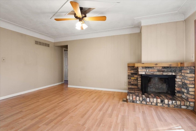 living area with visible vents, a fireplace with raised hearth, a ceiling fan, wood finished floors, and baseboards