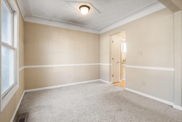 carpeted spare room with a healthy amount of sunlight, visible vents, and baseboards