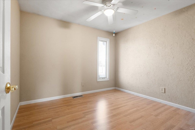 unfurnished room with ceiling fan, visible vents, light wood-type flooring, and baseboards