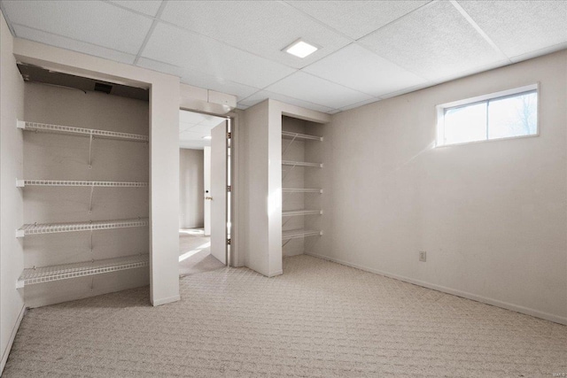 basement with baseboards, a paneled ceiling, and carpet