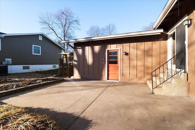 exterior space featuring central air condition unit, board and batten siding, and a patio