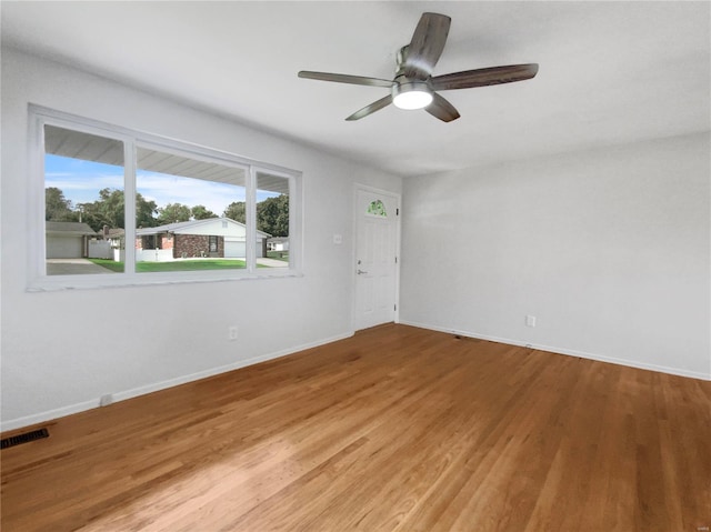 empty room featuring hardwood / wood-style floors, ceiling fan, and a healthy amount of sunlight