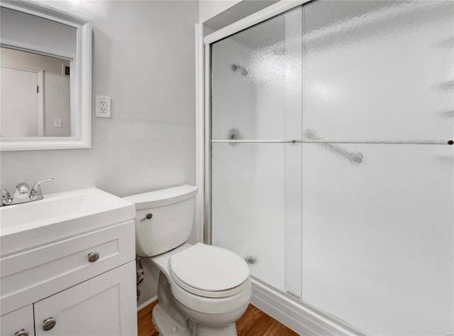 bathroom with vanity, toilet, hardwood / wood-style flooring, and a shower with shower door