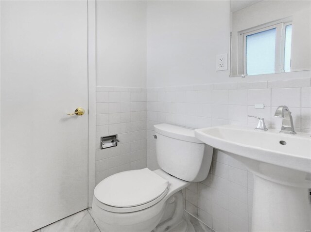 bathroom with tile patterned flooring, tile walls, and toilet