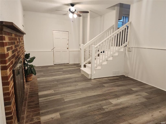 interior space featuring wood-type flooring, a brick fireplace, and ceiling fan