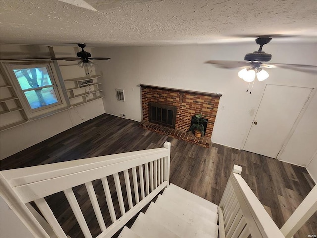 interior space with ceiling fan, hardwood / wood-style flooring, a fireplace, and a textured ceiling