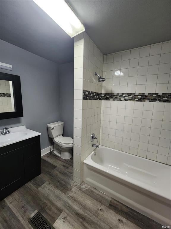 full bathroom with vanity, toilet, tiled shower / bath combo, and hardwood / wood-style flooring