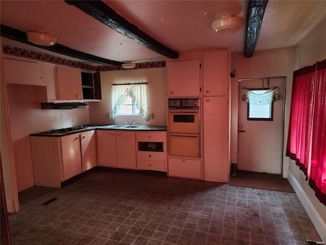 kitchen with beamed ceiling, oven, and sink