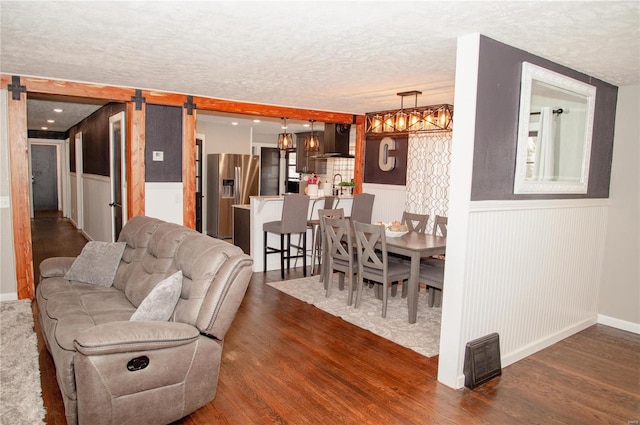 living room featuring a textured ceiling, dark wood-type flooring, and a barn door