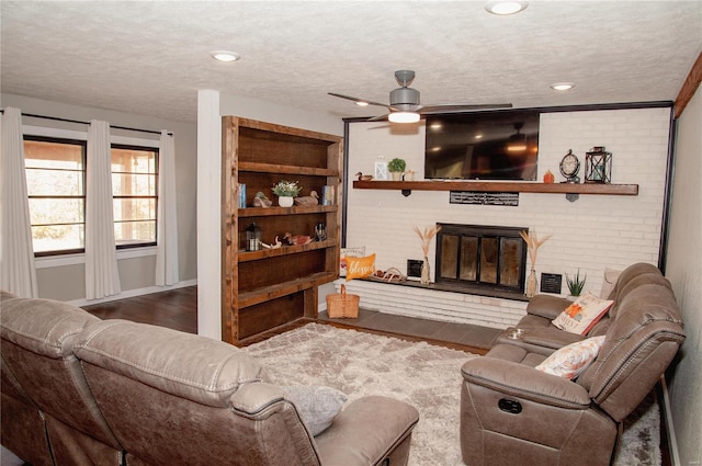 living room featuring a brick fireplace, a textured ceiling, and hardwood / wood-style flooring