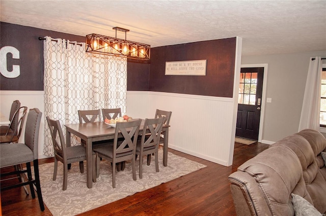 dining space with dark hardwood / wood-style floors, a textured ceiling, and a chandelier