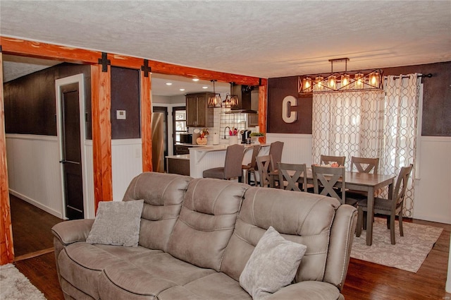 living room with dark wood-type flooring, a barn door, and a textured ceiling