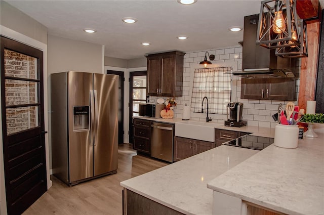 kitchen featuring light hardwood / wood-style flooring, sink, tasteful backsplash, appliances with stainless steel finishes, and decorative light fixtures