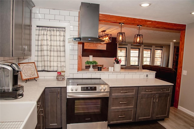 kitchen featuring hardwood / wood-style flooring, light stone counters, island range hood, stainless steel range with electric stovetop, and hanging light fixtures