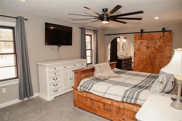 carpeted bedroom featuring a barn door, ceiling fan, and a textured ceiling