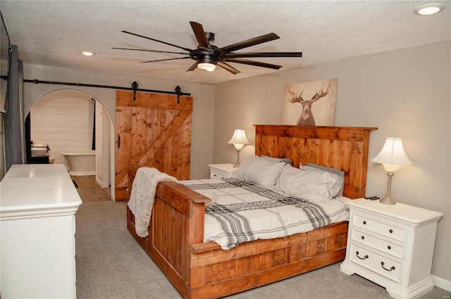 carpeted bedroom featuring a textured ceiling, a barn door, and ceiling fan