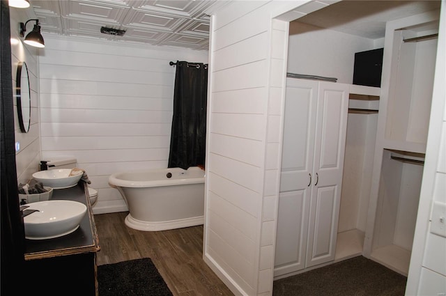 bathroom with toilet, wood walls, vanity, and hardwood / wood-style flooring