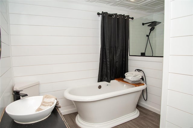 bathroom featuring wooden walls, hardwood / wood-style flooring, and a bathing tub