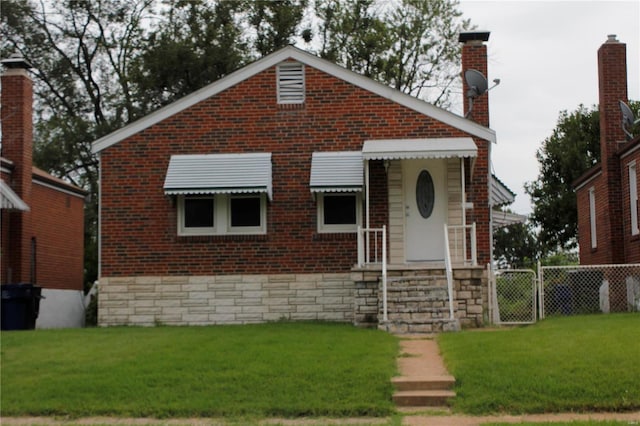 bungalow-style home featuring brick siding, fence, a gate, a chimney, and a front yard