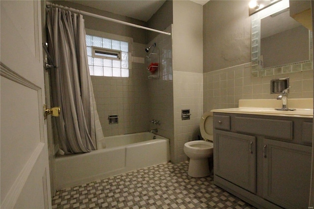 full bathroom featuring toilet, a wainscoted wall, shower / tub combo, vanity, and tile walls