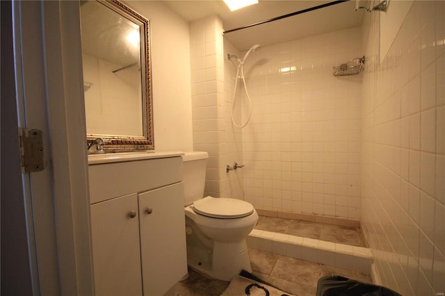 full bathroom with a tile shower, vanity, and toilet