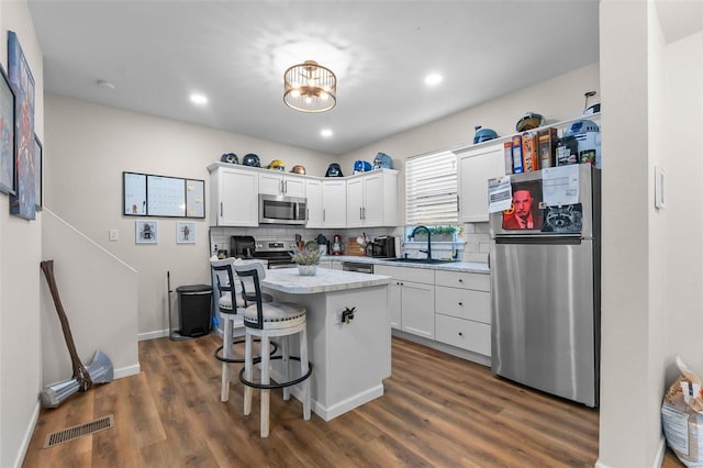 kitchen featuring a center island, sink, white cabinetry, a kitchen bar, and stainless steel appliances