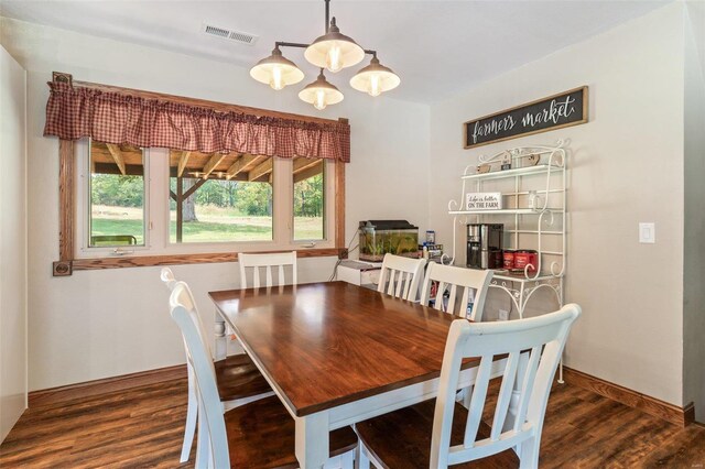 dining area with dark wood-type flooring and a notable chandelier