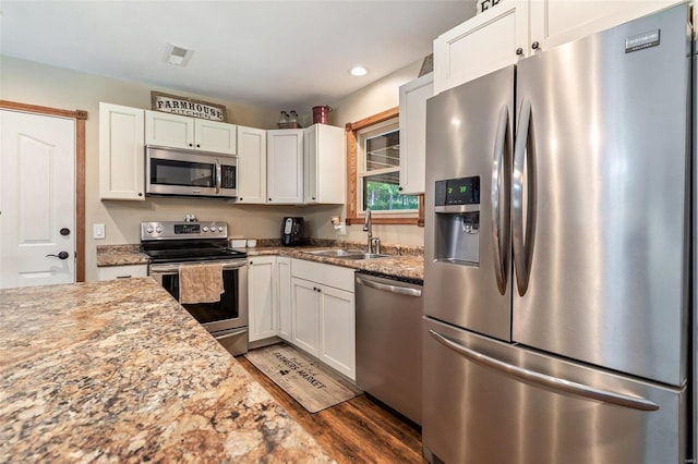 kitchen with hardwood / wood-style floors, appliances with stainless steel finishes, sink, light stone counters, and white cabinets