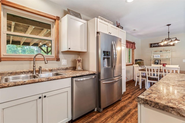 kitchen with white cabinets, decorative light fixtures, stainless steel appliances, sink, and dark wood-type flooring