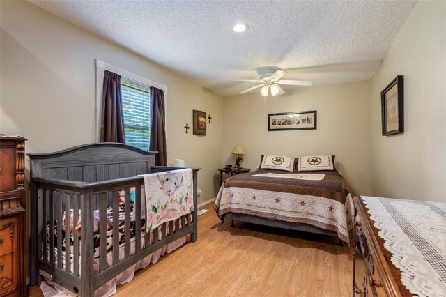 bedroom with a textured ceiling, ceiling fan, and light wood-type flooring