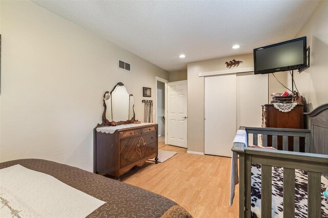 bedroom featuring a textured ceiling, a closet, and light hardwood / wood-style floors