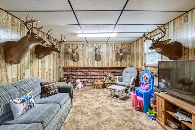 carpeted living room featuring wood walls and a paneled ceiling