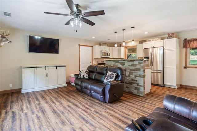 living area featuring visible vents, baseboards, ceiling fan, and wood finished floors