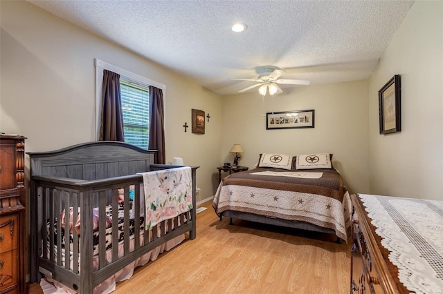 bedroom with light wood-style flooring, a ceiling fan, baseboards, and a textured ceiling