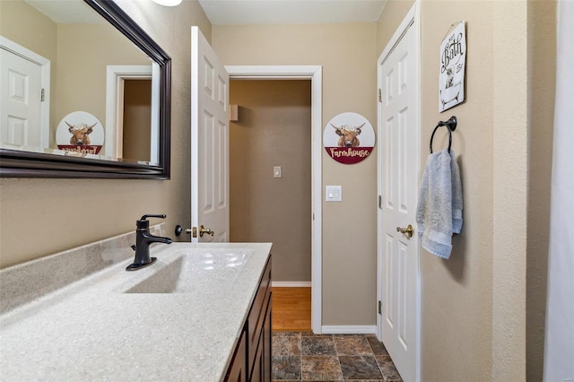 bathroom featuring vanity, stone finish floor, and baseboards