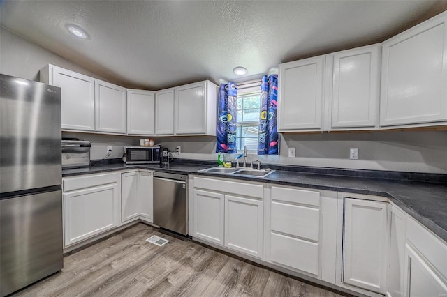 kitchen with light wood-type flooring, white cabinets, stainless steel appliances, and sink