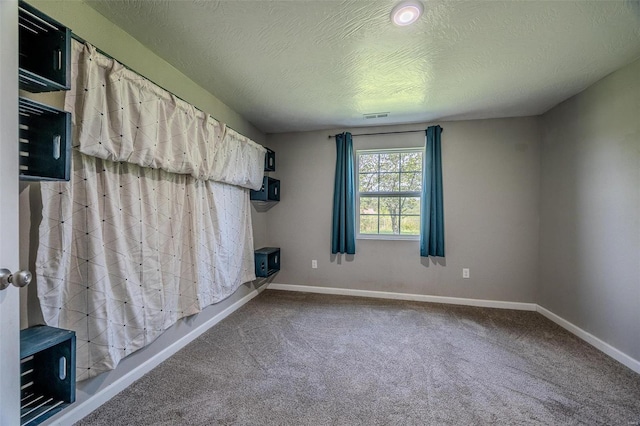 empty room featuring a textured ceiling and carpet